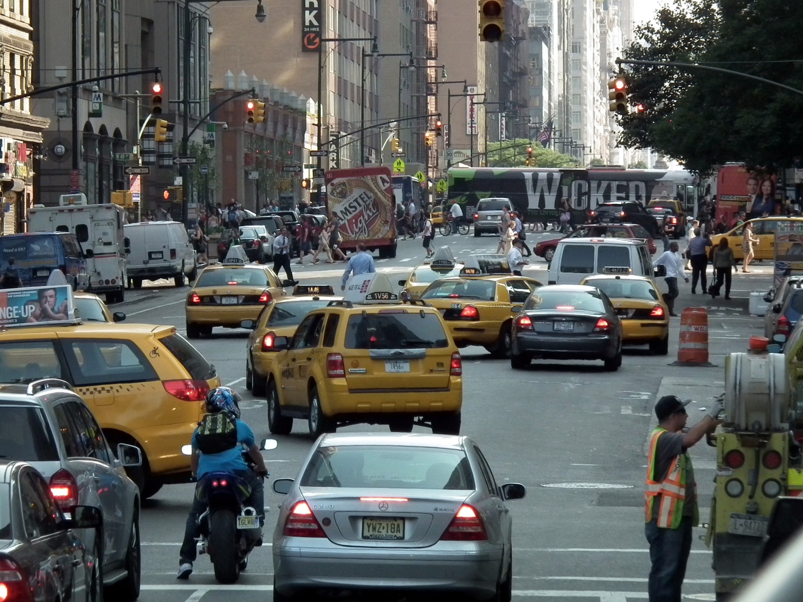 Vehicles and pedestrians on a street between Manhattan buildings