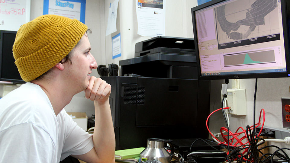 A NOAA scientist interpreting sonar data on shipboard monitors